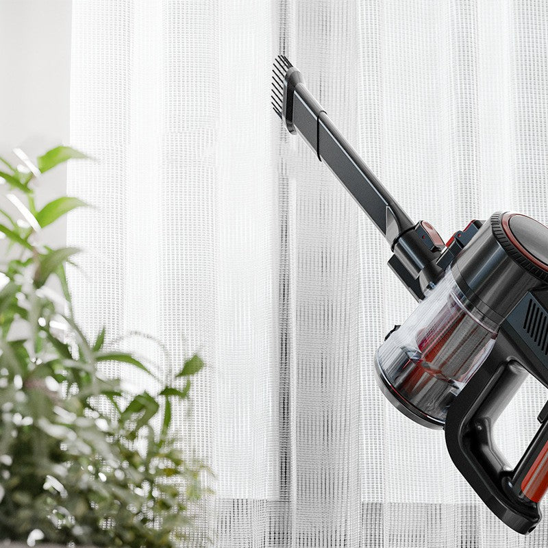 Handheld vacuum with a brush attachment beside a curtain